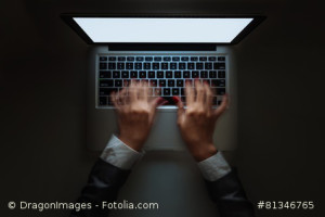 Blurred motion of hands typing on laptop late at night, view from above